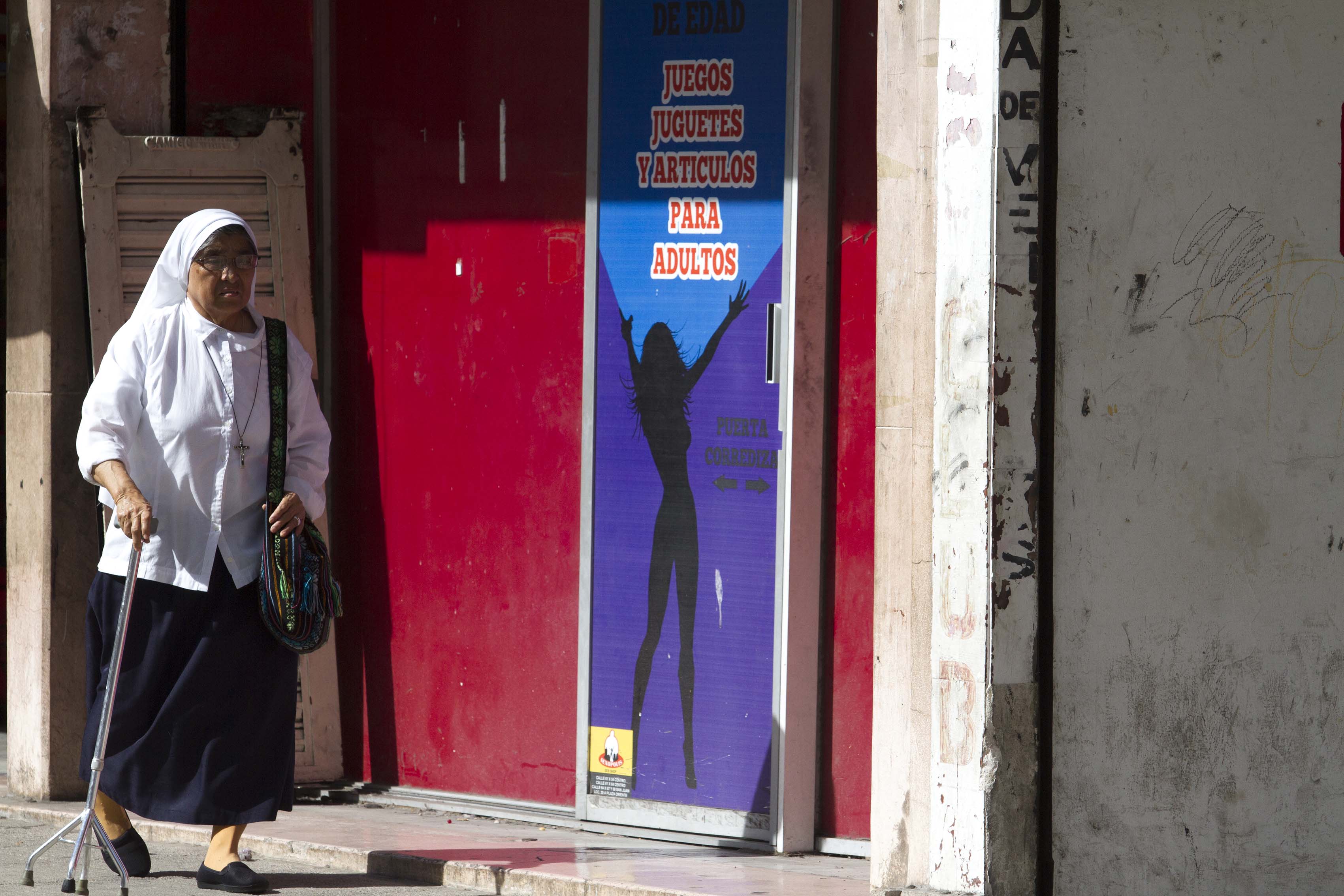 Monja pasando por una tienda sexshop