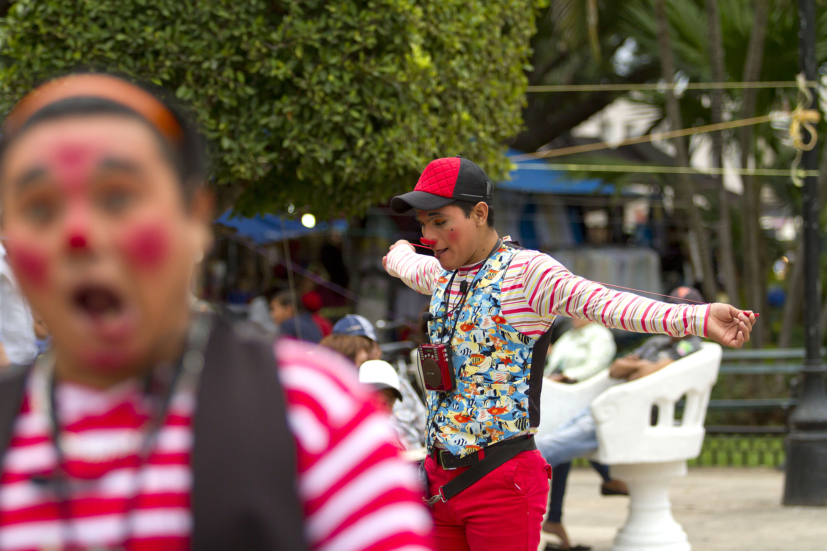 Payasos realizan actos para sorprender a la gente en plaza grande