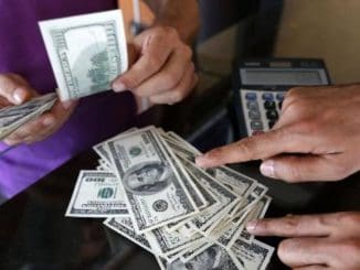 A money changer sells U.S. dollars to a customer in the border city of Hatay